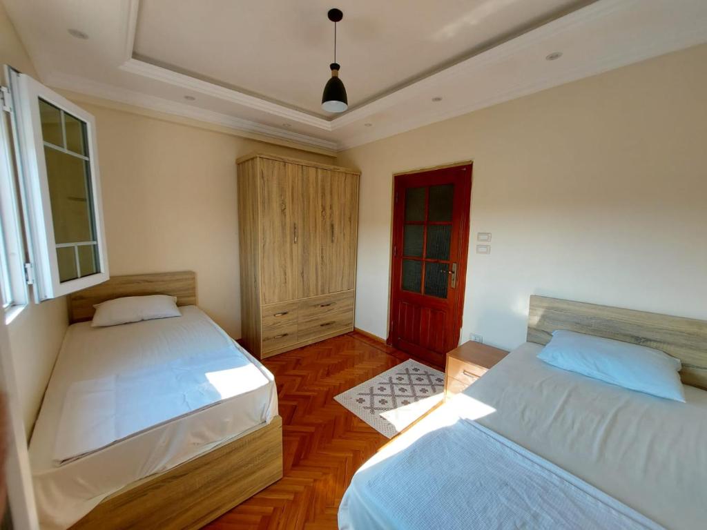 1 dormitorio con 2 camas y puerta roja en شقه فندقية رائعة في مركز مدينة الإسكندرية, en Alejandría