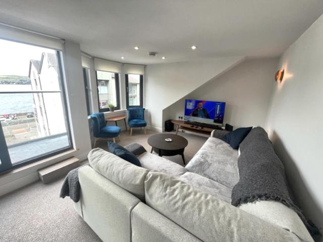 a living room with a couch and a tv at Crow’s Nest, Waverley Apartments in Gourock