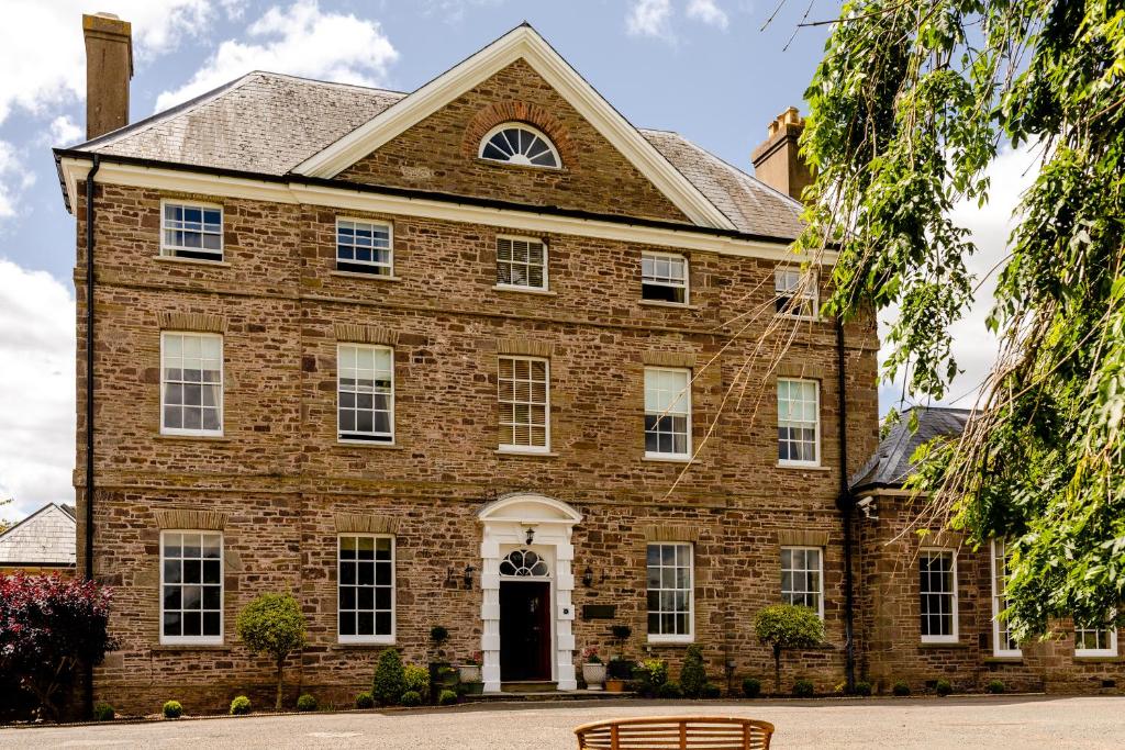 a large brick house with a bench in front of it at Peterstone Court Country House Restaurant & Spa in Brecon