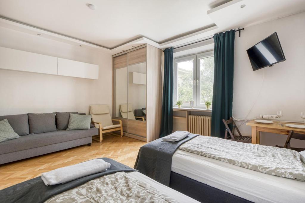 a living room with two beds and a couch at Labo Apartment Ogrodowa in Warsaw