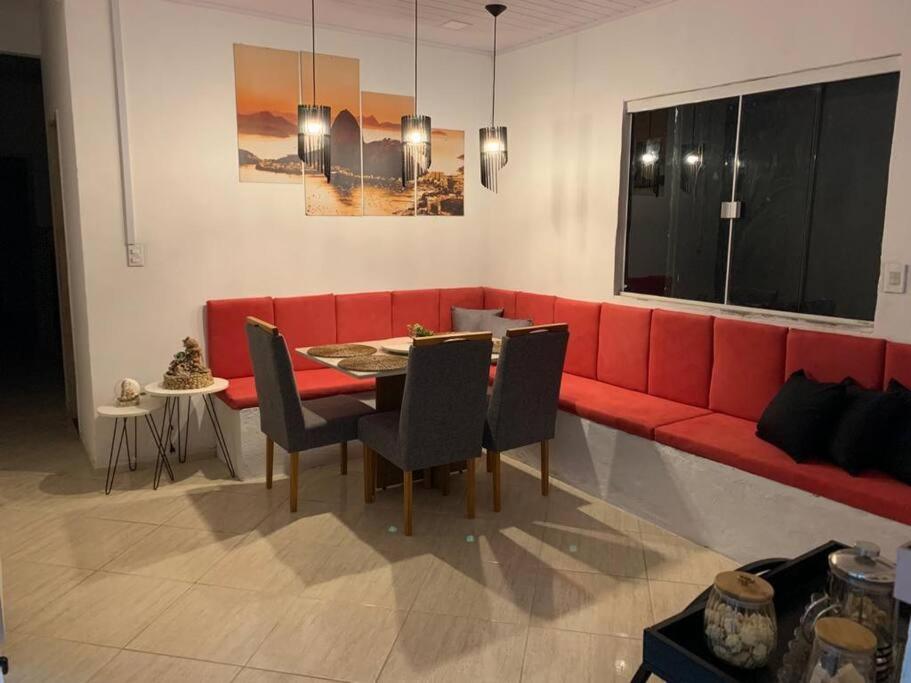 sala de estar con sofá rojo, mesa y sillas en Aluguel por temporada Unamar, en Tamoios