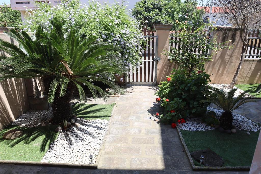 un jardín con 2 palmeras y una valla en Orticello Appartment, en San Sperate