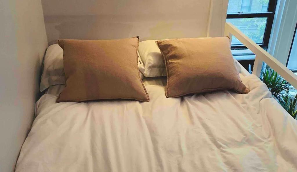 Una cama blanca con dos almohadas encima. en Charming Studio West Village en Nueva York