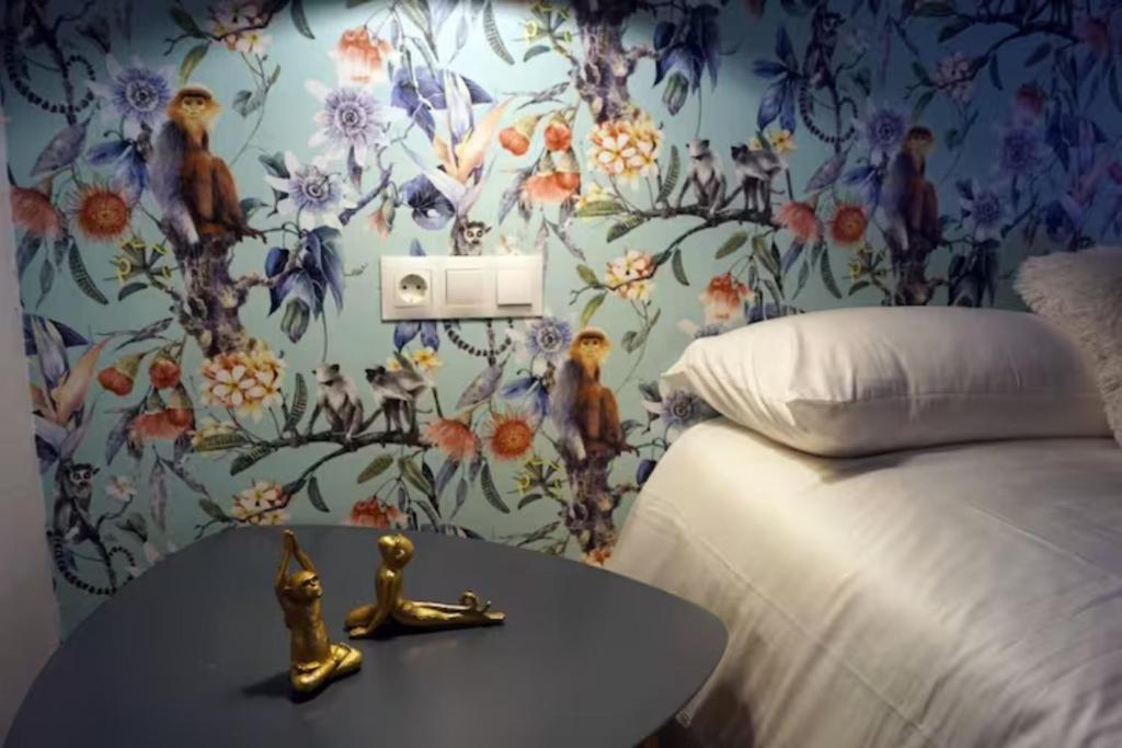 a bedroom with a bed and a table with a flower wallpaper at Habitación de Matrimonio - Apartamento in Estella