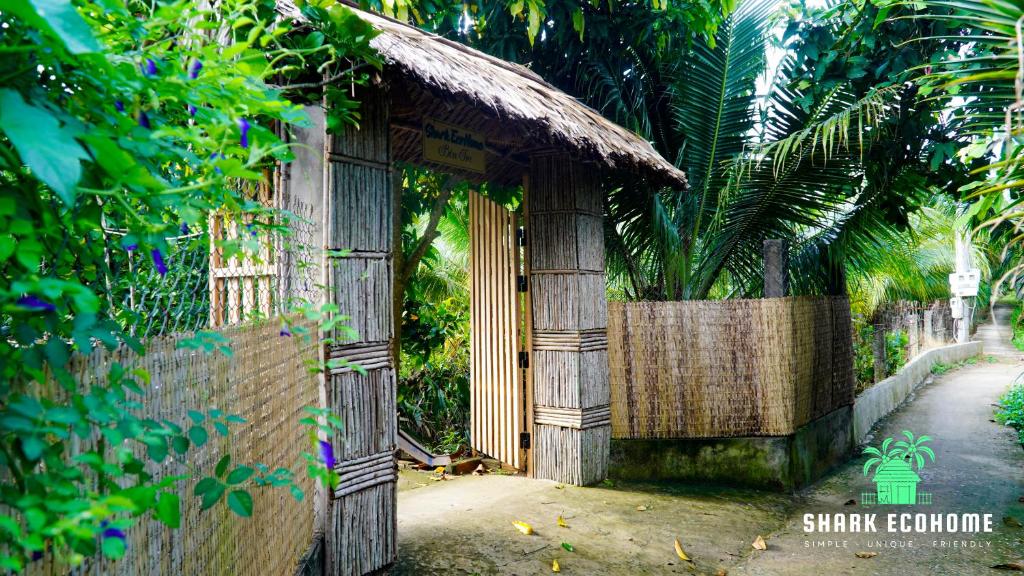 een ingang naar een gebouw met een hek en bomen bij SHARK ECOHOME BẾN TRE in Ấp Phong Phú