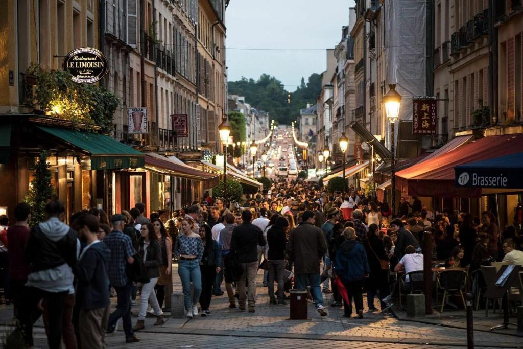 una multitud de personas caminando por una calle de la ciudad por la noche en Le Versailles suite en Versalles