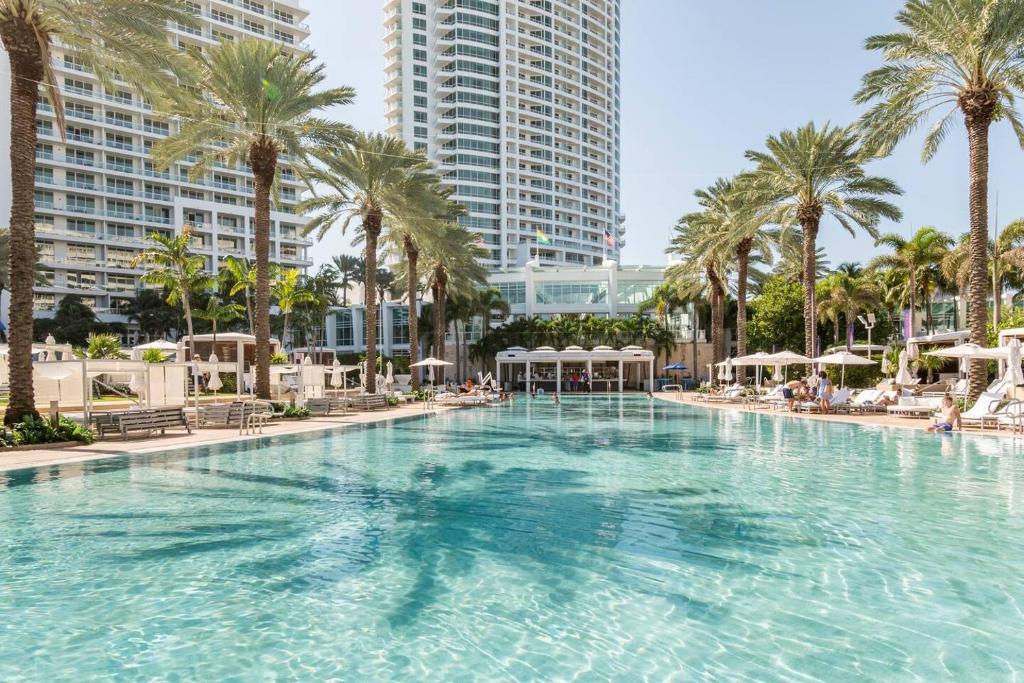 a large swimming pool with palm trees and buildings at Fontainebleau #1 Luxury Relax in Miami Beach