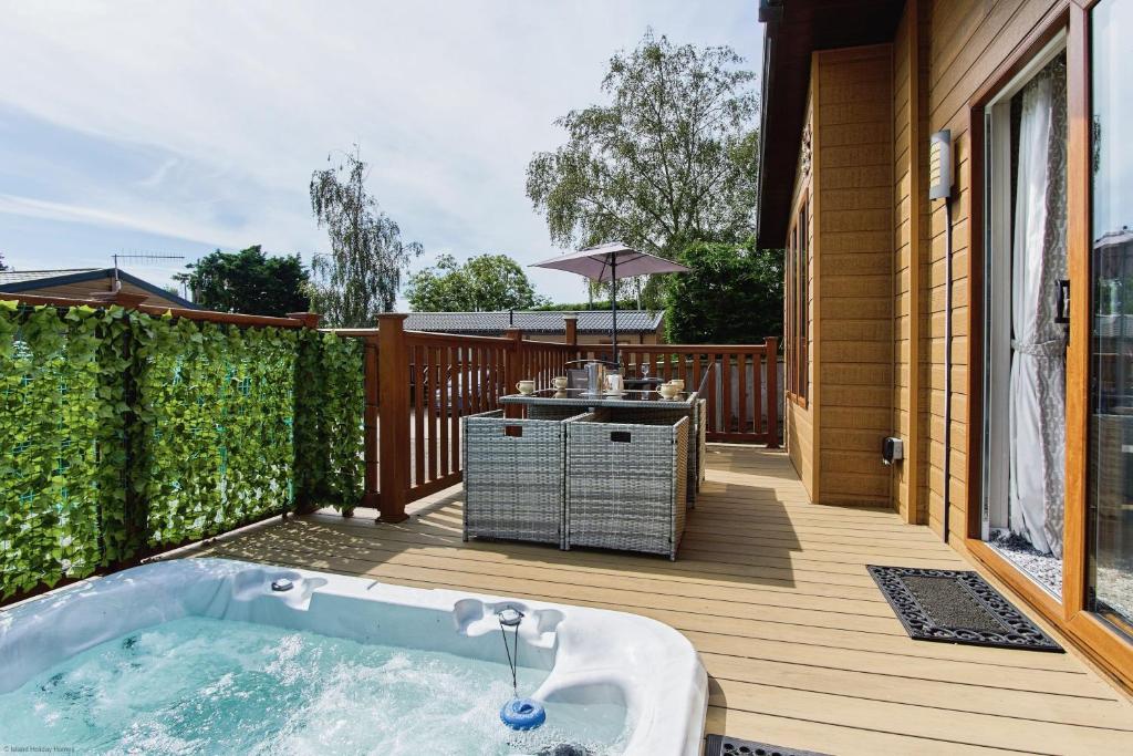 a hot tub on a deck with a grill at The Lodge in Ryde
