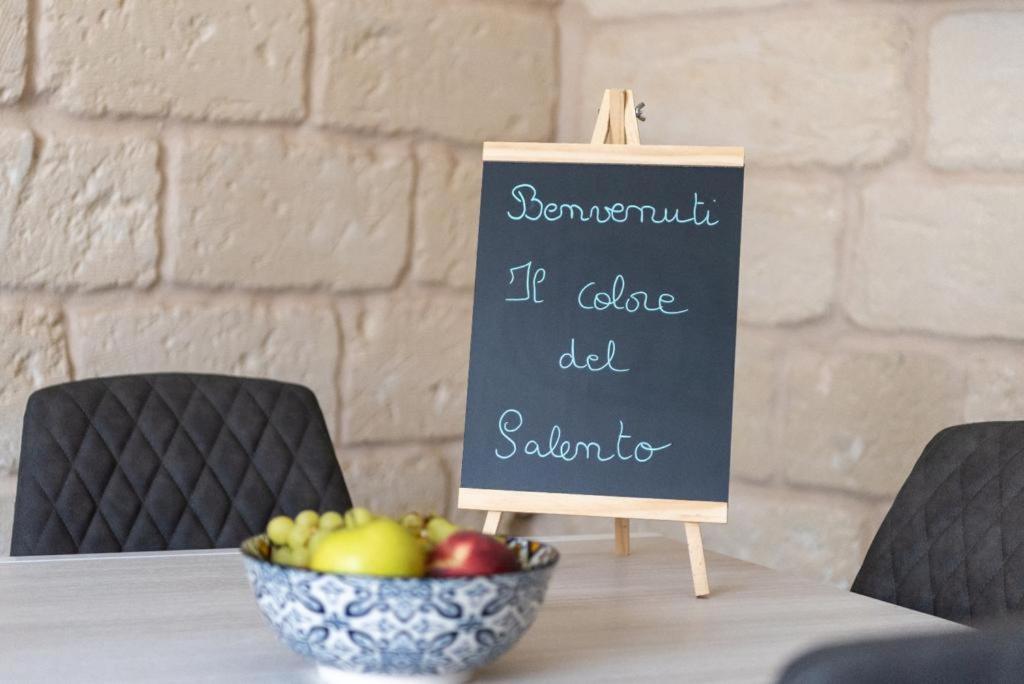 una mesa con un bol de fruta y una pizarra en Il colore del Salento, en Carpignano Salentino