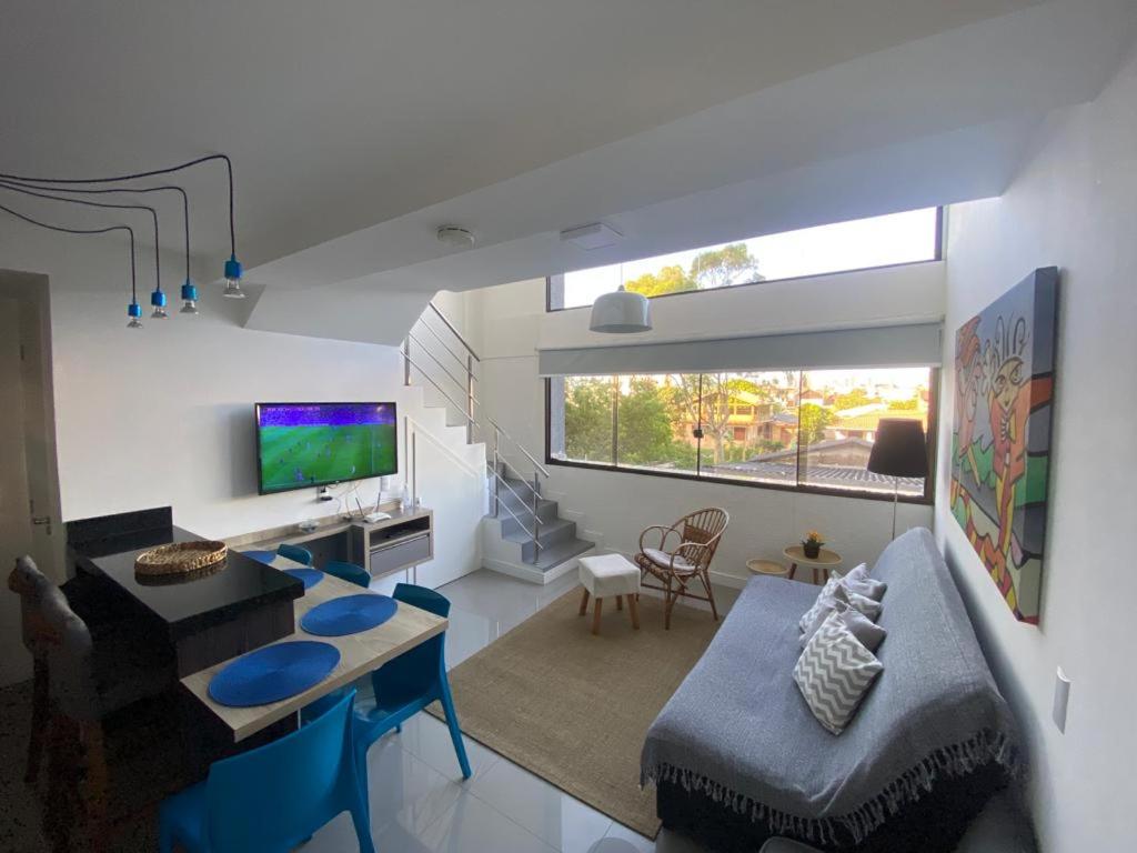 sala de estar con sofá, mesa y TV en Loft Premium Torres RS, en Torres
