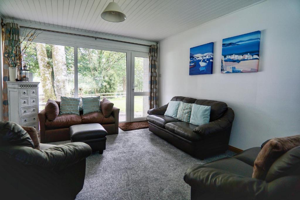 a living room with leather furniture and a large window at Special 2 Bedroom Home in White Cross in Saint Columb Major