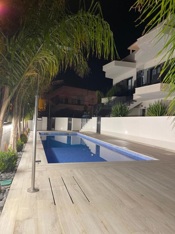 a swimming pool in front of a building with palm trees at Mar Menor Elisa Apartment in Santiago de la Ribera