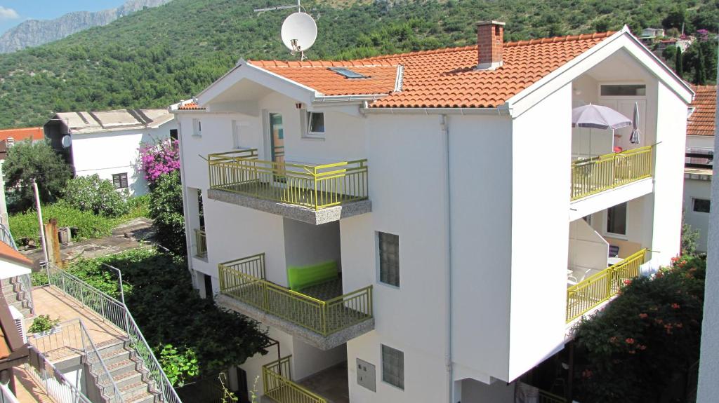 a white apartment building with balconies and a mountain at Apartments Primorac Podaca in Podaca