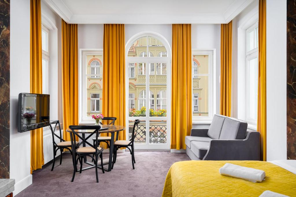ソポトにあるSo in Sopot Apartmentsの黄色いカーテン、テーブルと椅子が備わる客室です。