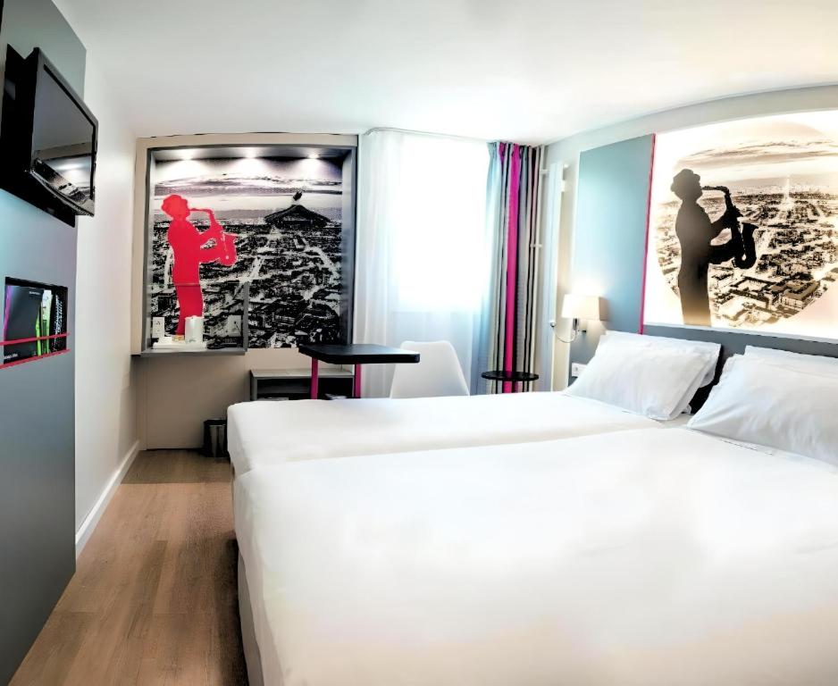 a hotel room with two beds and a picture on the wall at Kyriad Paris Saint Ouen in Saint-Ouen