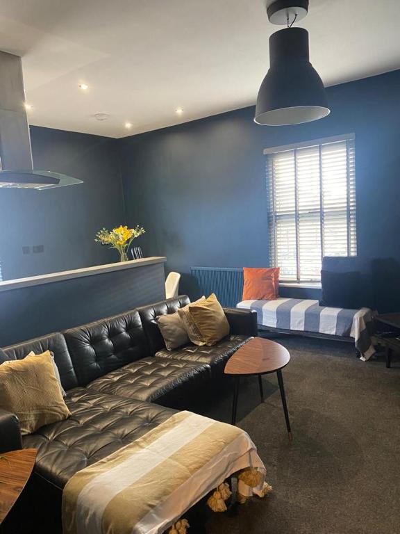 a living room with a black leather couch and a blue wall at Raby Apartment in Darlington