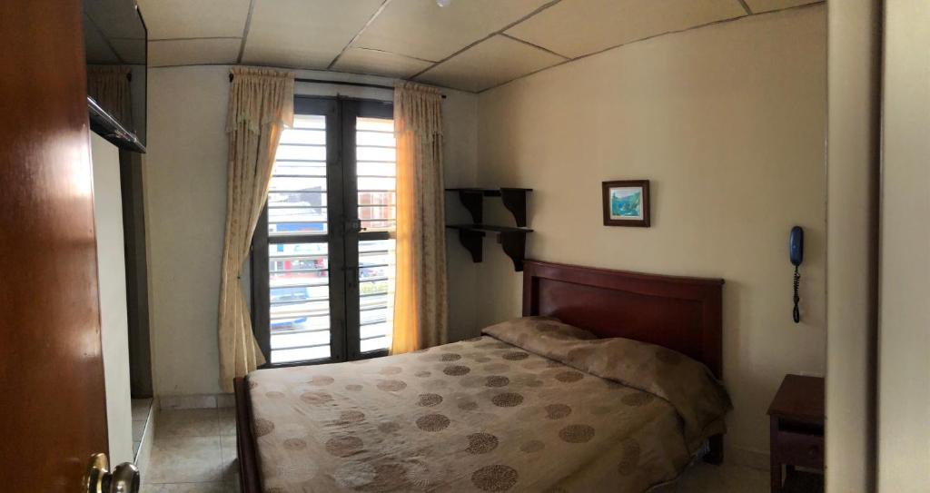 um quarto com uma cama e uma janela em HOTEL TORRELUZ PLAZA em Popayán