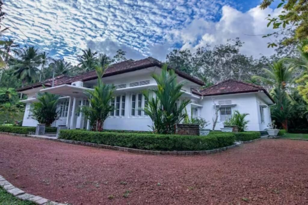 a white house with palm trees and a driveway at Village Headman's Five Bedrooms Entire Bungalow in Bentota