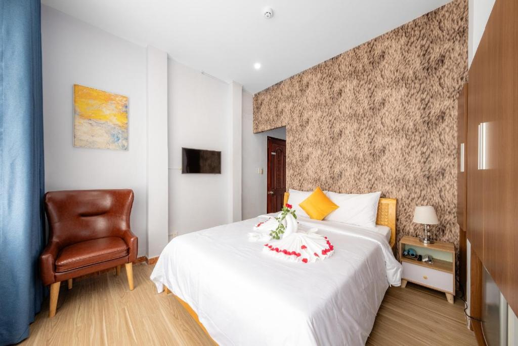 een slaapkamer met een wit bed en een stoel bij Ha Vy Hotel in Ho Chi Minh-stad