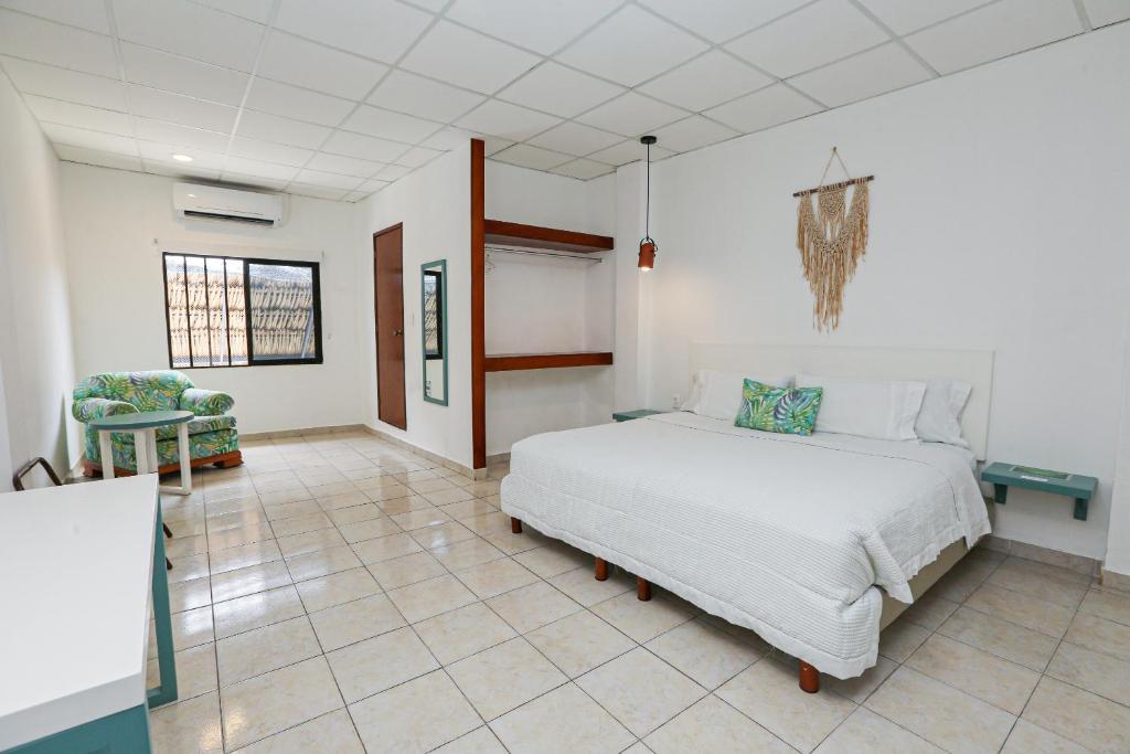 a bedroom with a white bed and a tiled floor at Hotel & Suites Arges - Centro Chetumal in Chetumal