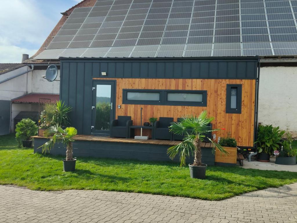 a tiny house with a solar roof with palm trees at Mariolas Tinyhouse in Markt Nordheim