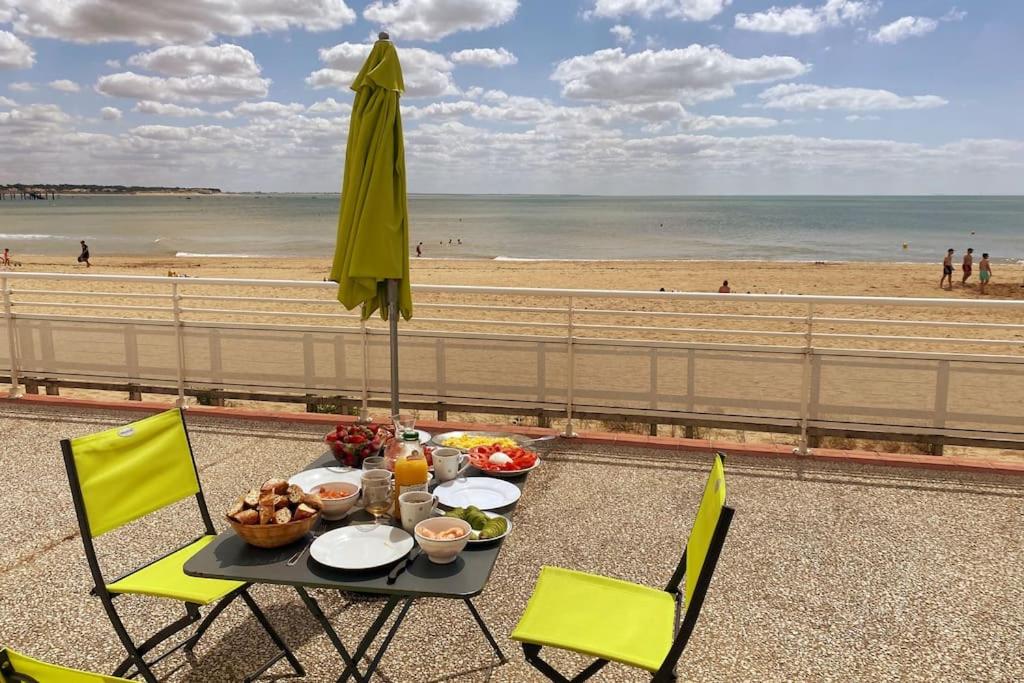 een tafel met eten en een parasol op het strand bij Superbe appartement les pieds dans l'eau ! in La Tranche-sur-Mer