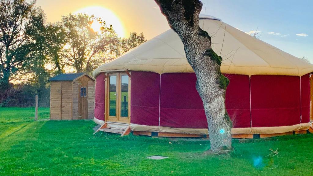 a red and white tent in a field with a tree at Yourte proche canal in Saffré