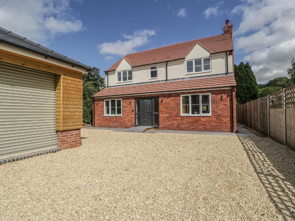 a detached house with a garage on a gravel driveway at Ranbir House in Longhope