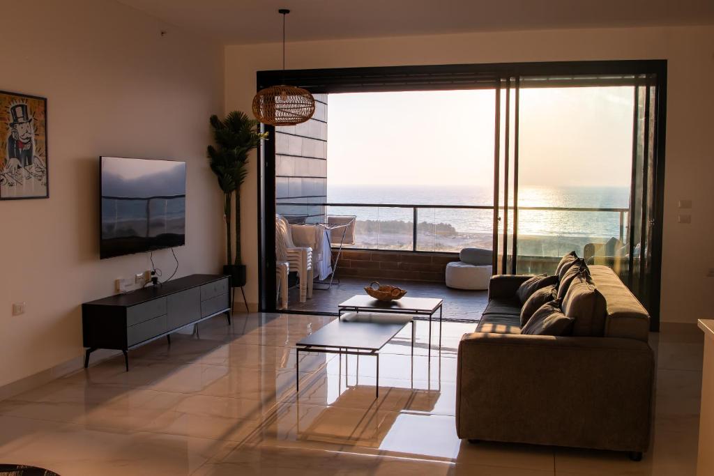 een woonkamer met een bank en uitzicht op de oceaan bij דירת 5 חדרים בבניין הכי טוב בעיר עם נוף מרהיב לים in Ashdod