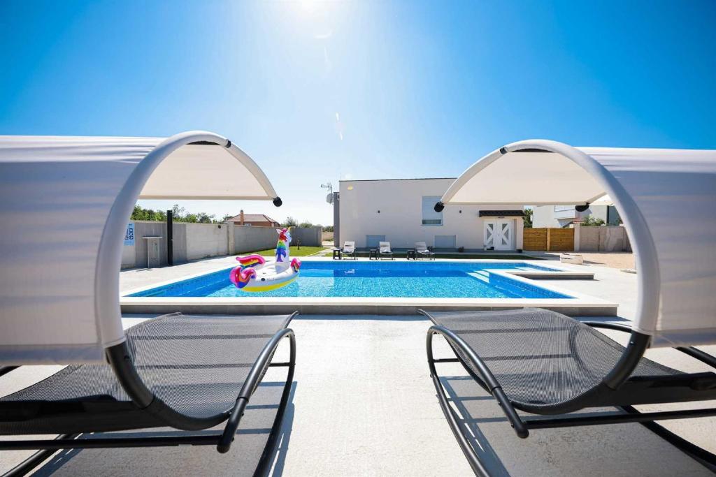 a pair of chairs sitting next to a swimming pool at Villa Miranda with pool in Zaton