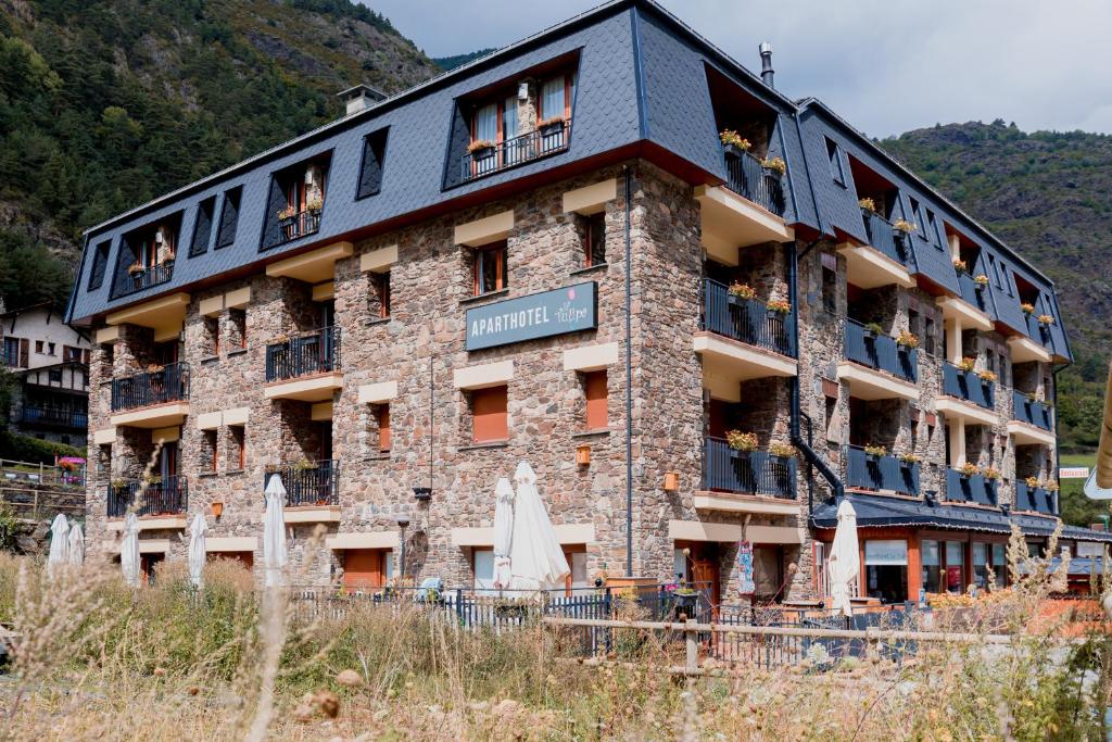 ein großes Backsteingebäude mit Menschen auf dem Balkon in der Unterkunft Pierre & Vacances Aparthotel La Tulipa in Ordino