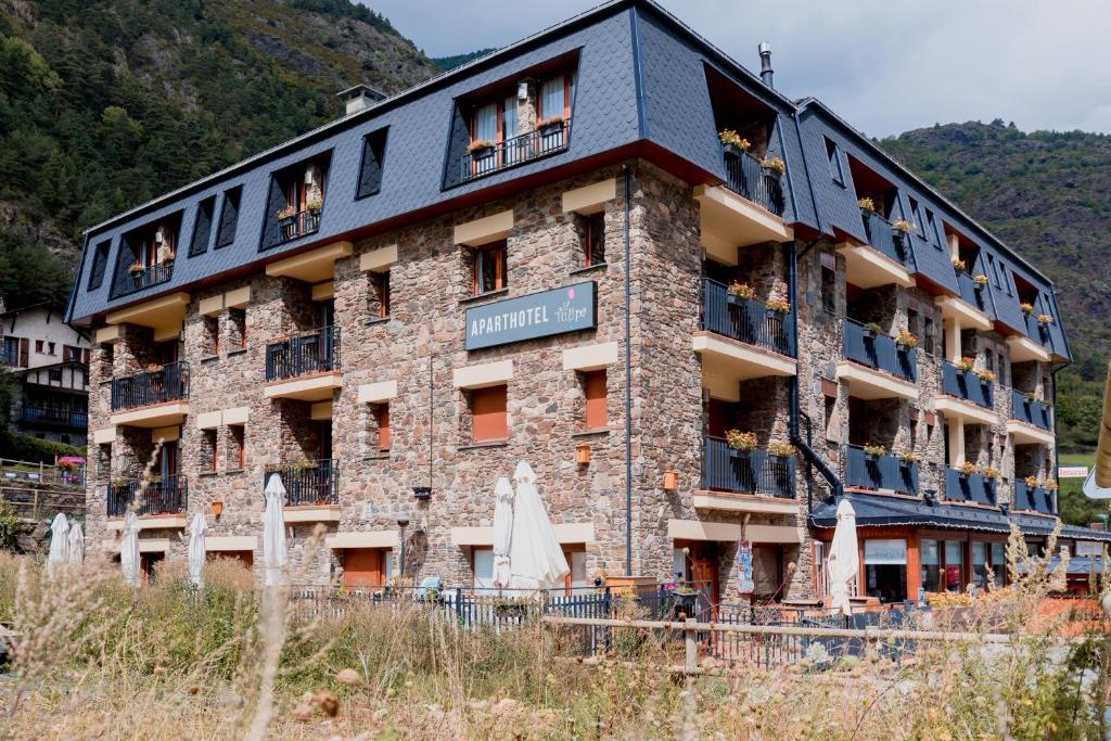 um grande edifício de tijolos com pessoas na varanda em Pierre & Vacances Aparthotel La Tulipa em Ordino