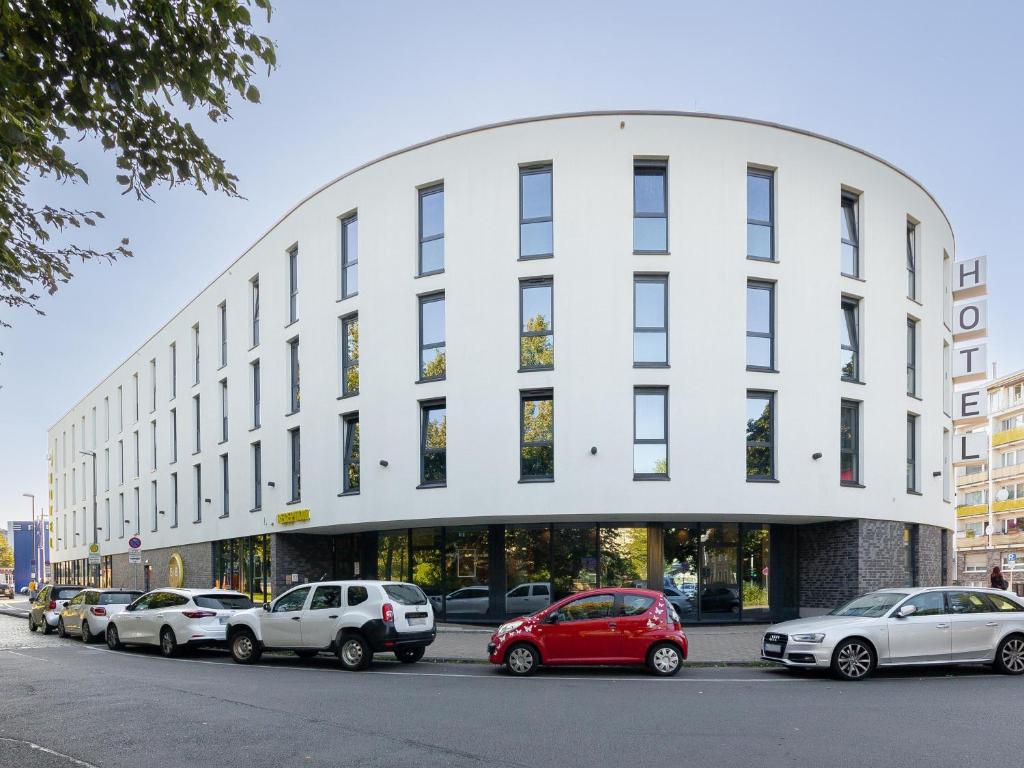 ヴッパータールにあるB&B HOTEL Wuppertal City-Südの車が目の前に停まった白い建物