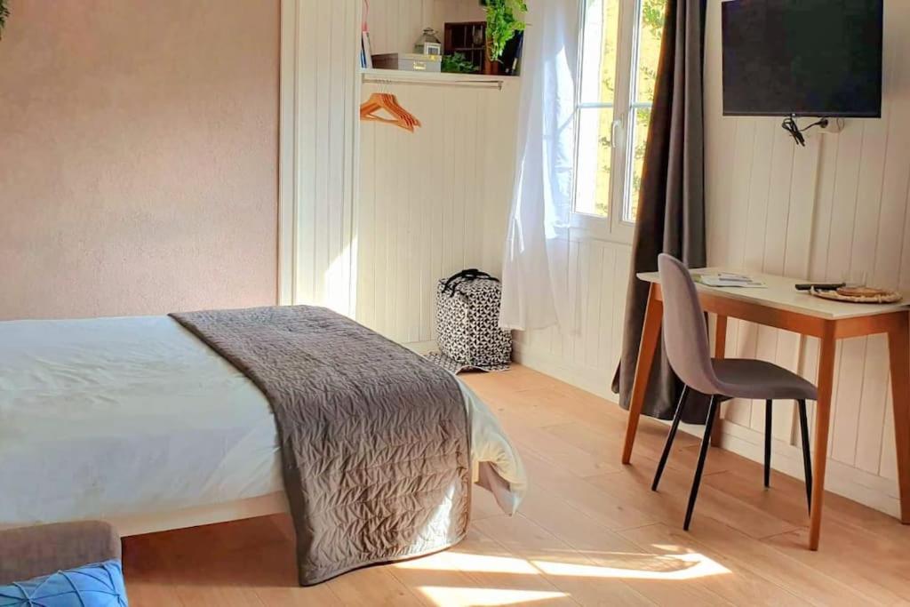 um quarto com uma cama, uma secretária e uma cadeira em studio cosy 1er centre Laval vu château et jardin em Laval