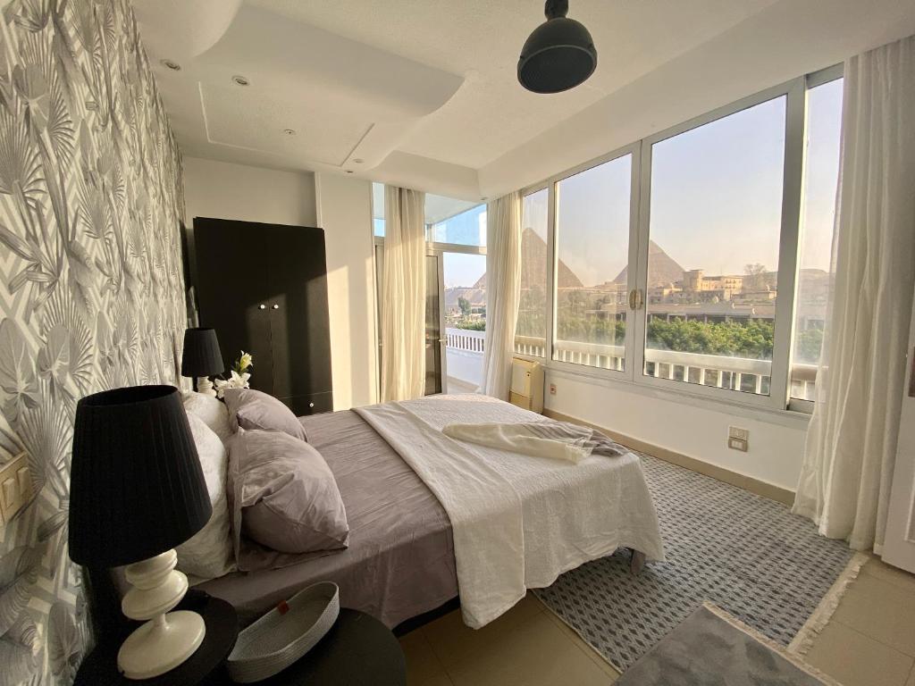 a bedroom with a bed and a large window at The Pyramid Area Vibe in Cairo