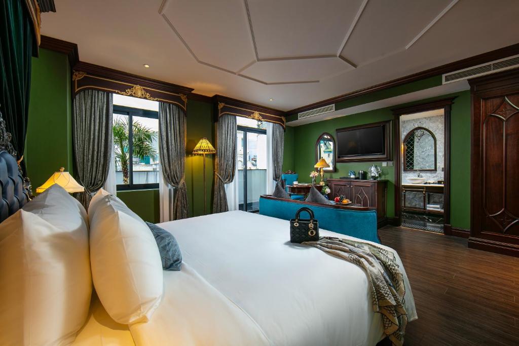 a bedroom with a large white bed with green walls at Le Chanvre Hanoi Hotel & Spa in Hanoi