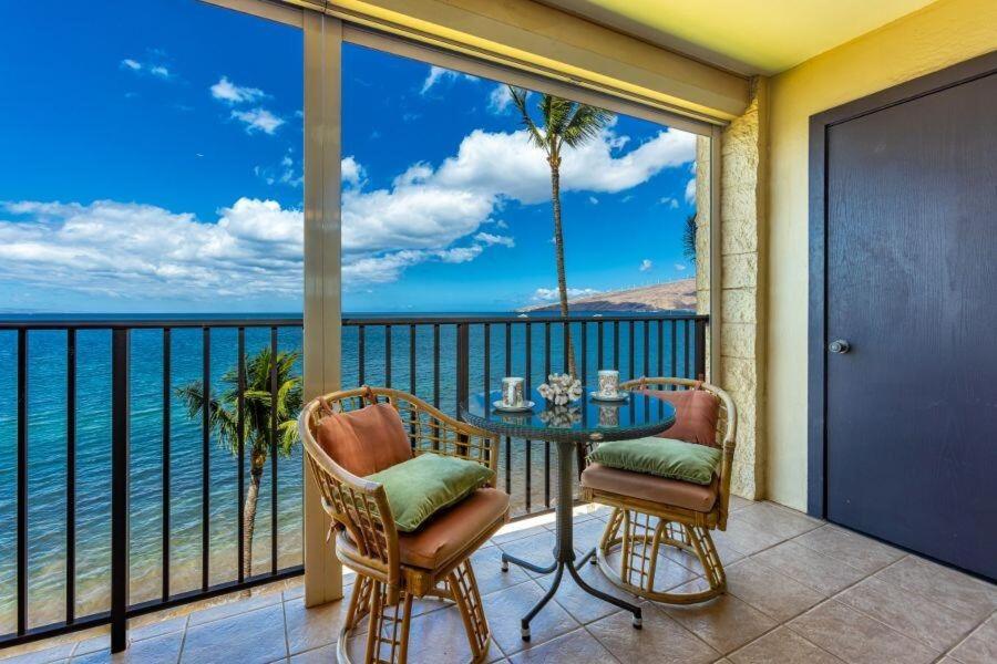 a balcony with a table and chairs and the ocean at KIHEI BEACH, #507 condo in Kihei