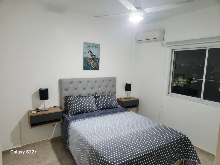 um quarto branco com uma cama e duas mesas de cabeceira em Departamento muy comodo y lindo em Corrientes