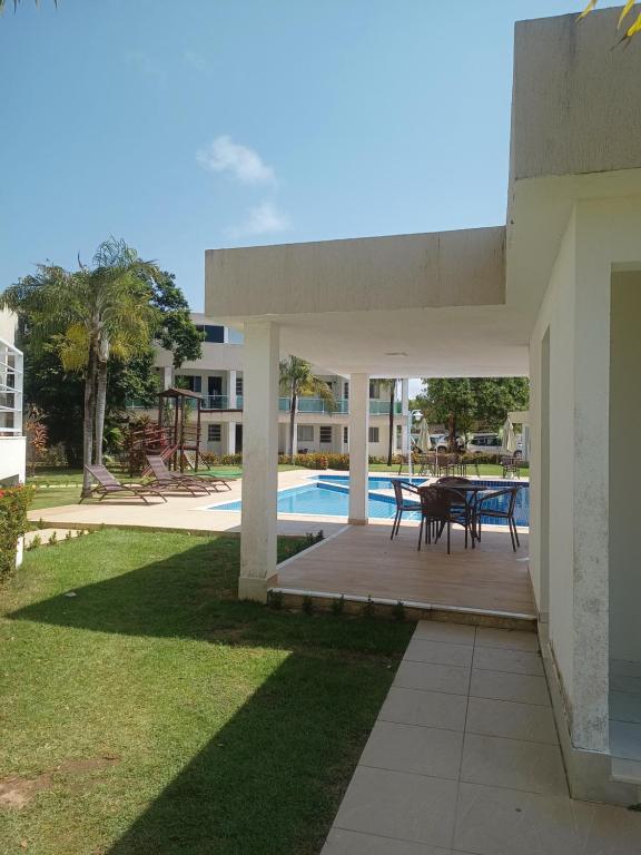 un patio con mesa y sillas junto a una piscina en Bella casa 10 em Guarajuba, apartamento equipado para você e sua família, tudo que você precisa pra se sentir em casa! en Guarajuba