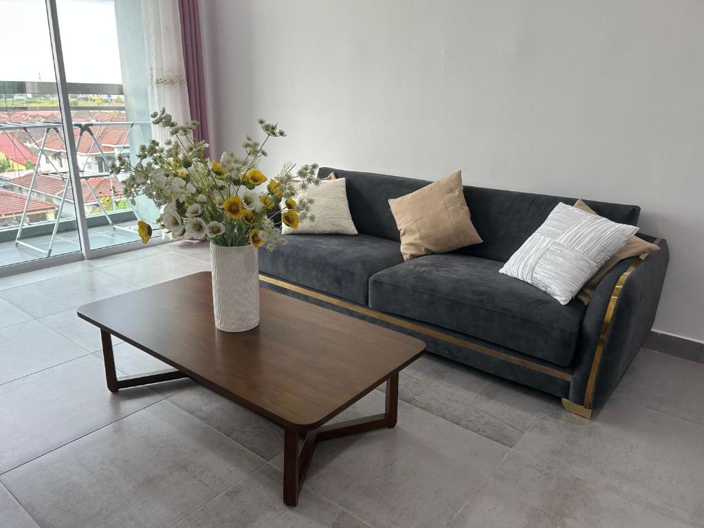 a living room with a couch and a table with flowers at P3 Great value, cozy, convenient in city! in Kuching