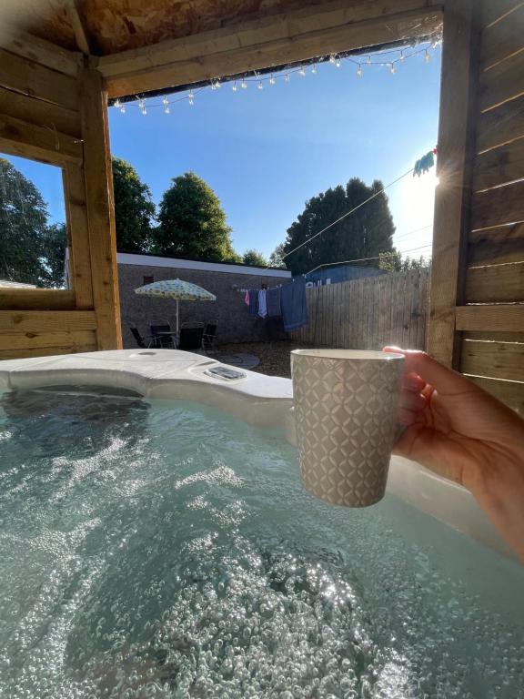 a person holding a cup in a hot tub at Delightful 2 bed with hot tub and historic ruin. in Dumfries