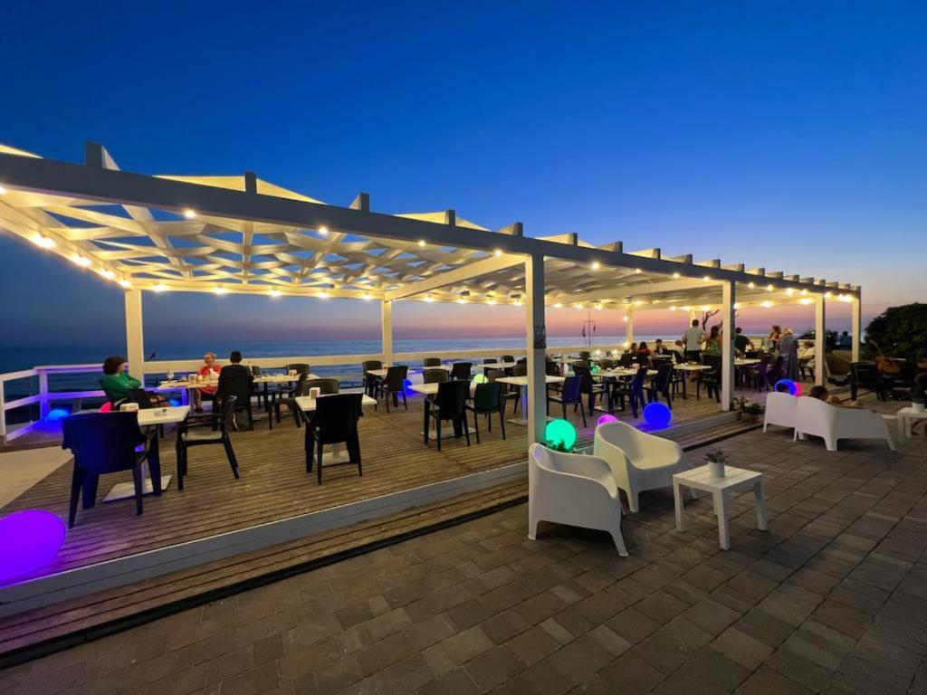 a deck with tables and chairs and people on the beach at Hotel Sirenetta in Anzio
