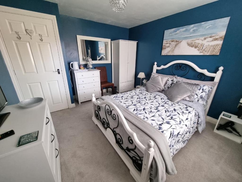 a bedroom with a white bed and a blue wall at Dungarvon House B&B, Exclusive Bookings Only, Hot tub, Garden & Summerhouse, EV Point in Weston-super-Mare