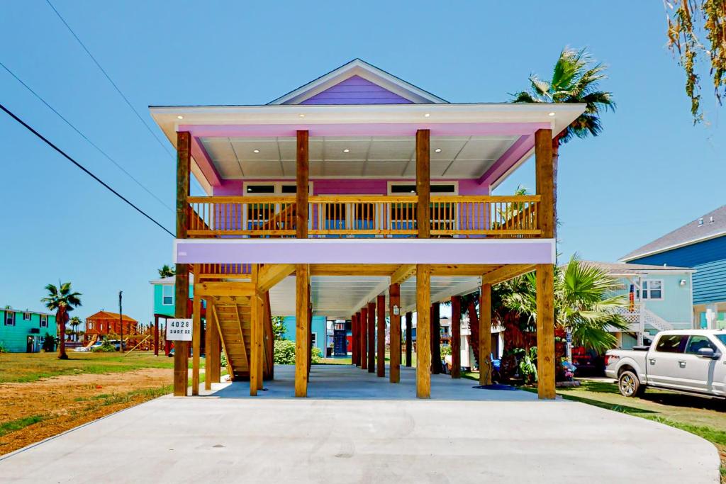 uma casa cor-de-rosa com um deque numa rua em The Purple Pelican em Galveston