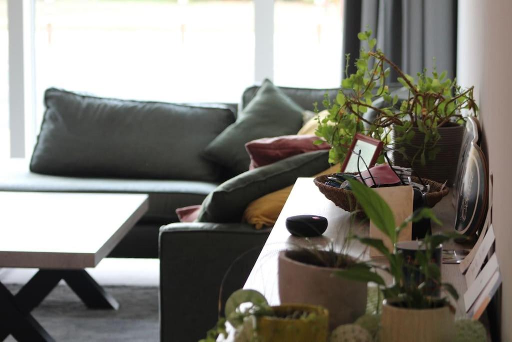 a living room with a couch and a table with plants at Ruim nieuwbouwappartement oostduinkerke in Oostduinkerke