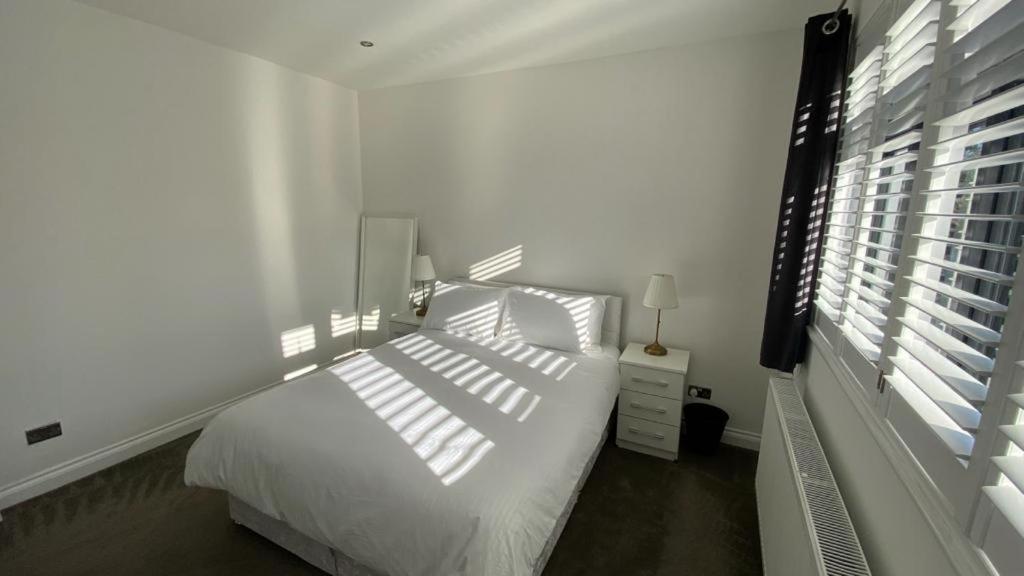a white bedroom with a white bed and a window at Roomy 2 bed flat in London in Thornton Heath