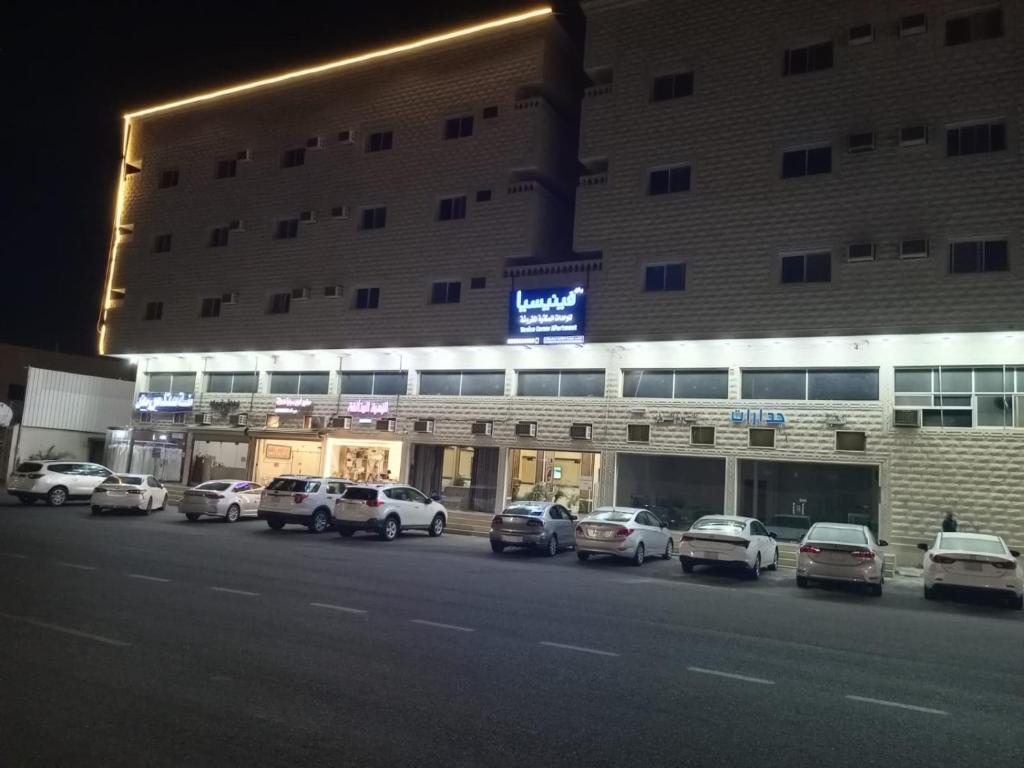 a parking lot with cars parked in front of a building at ركن فينيسيا للشقق المخدومة in Hail