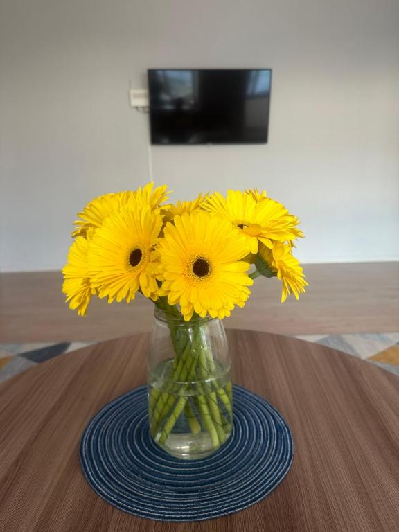 un jarrón lleno de flores amarillas en una mesa en Уютная и комфортная 3х комнатная в новом центре en Oral