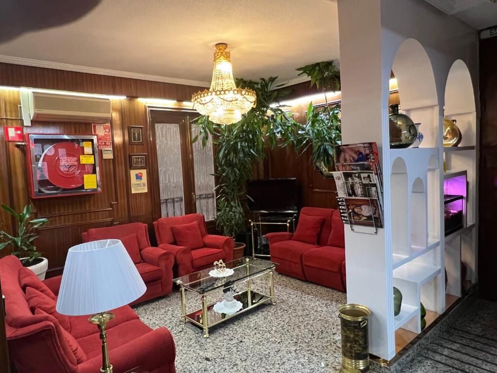 a living room with red furniture and a chandelier at Hostal Sonsoles Madrid-Centro in Madrid