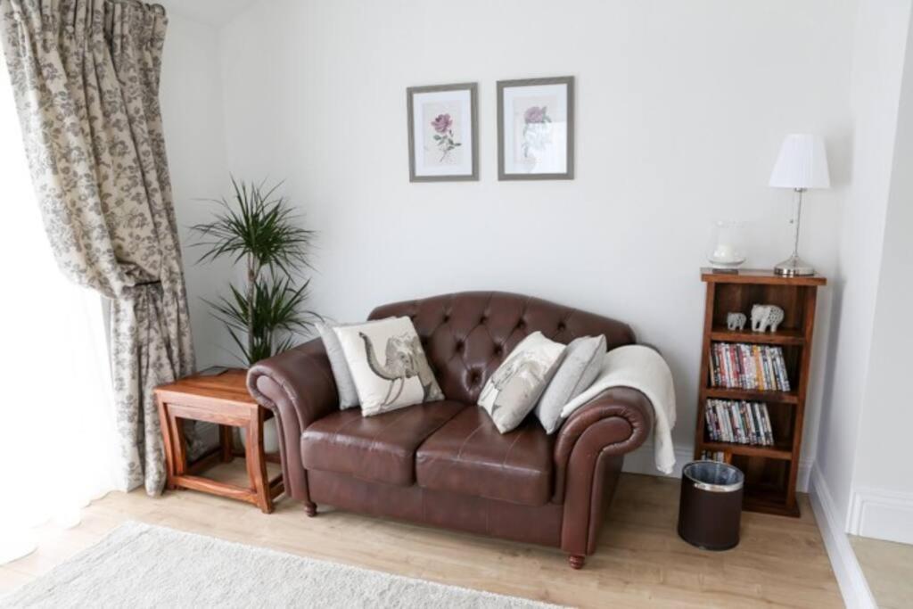 a brown leather couch in a living room at Detached Cotswold Stone Coach House in Cheltenham